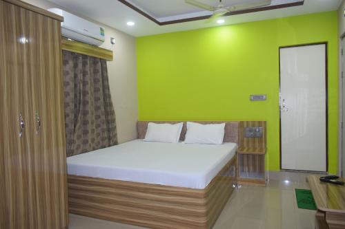 uma cama num quarto com uma parede verde em Airport Lodge em Siliguri