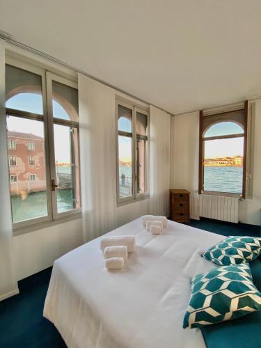 a bedroom with a large white bed with windows at Al Ponte Lungo - Giudecca in Venice