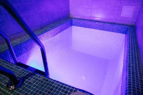 a large pool of water in a bathroom with purple lights at GasthauS & SPA in Bukovel