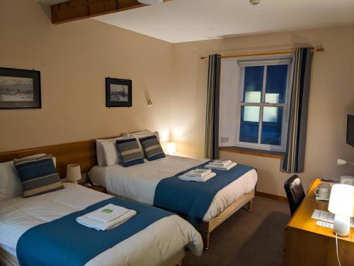 a hotel room with two beds and a window at Ferry Inn in Stromness