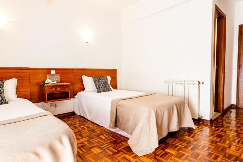 a bedroom with two beds and a wooden floor at Dona Amélia Hotel by RIDAN Hotels in Fátima