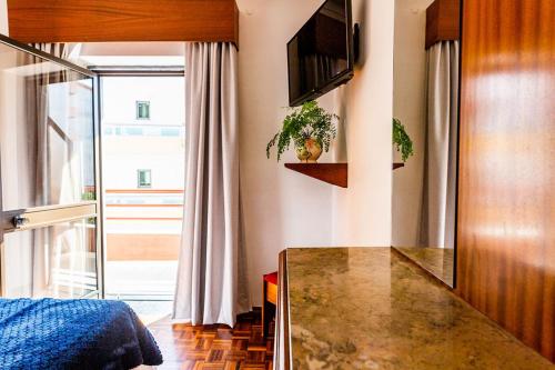 a kitchen with a counter and a television in a room at Dona Amélia Hotel by RIDAN Hotels in Fátima