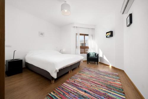 a bedroom with a white bed and a rug at Terraços do Rio by CORAL in Portimão