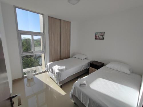 a hotel room with two beds and a window at Edificio Atlantis Tower, Confortable y Agradable in Santa Cruz de la Sierra