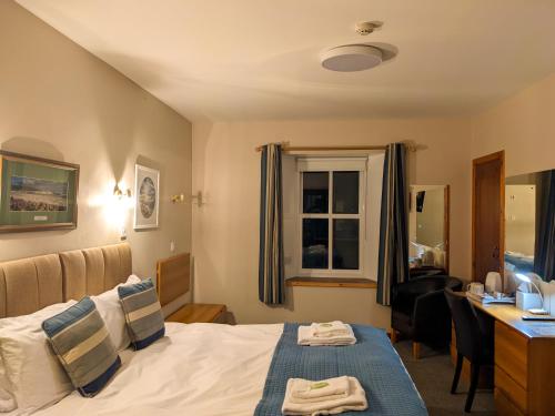 a hotel room with a bed and a desk and a window at Ferry Inn in Stromness