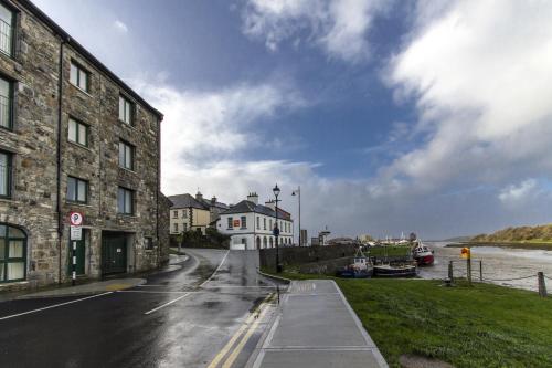 an empty street next to a river with buildings at The Helm Apartments B&B in Westport