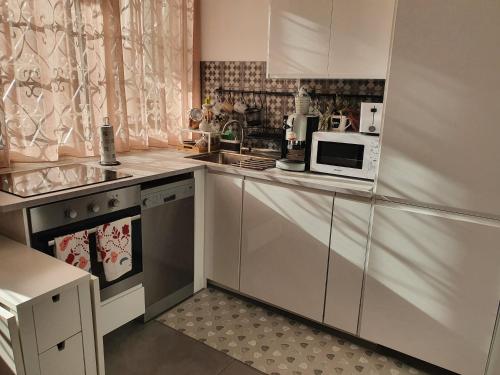 a kitchen with white cabinets and a microwave at Casa Monì in Naples