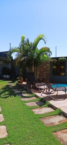 a walkway with benches and palm trees in a yard at Pousada Casa Bom Sono in Foz do Iguaçu