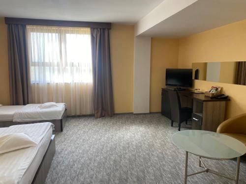 a hotel room with two beds and a desk and a table at Hotel Edelweiss in Mediaş