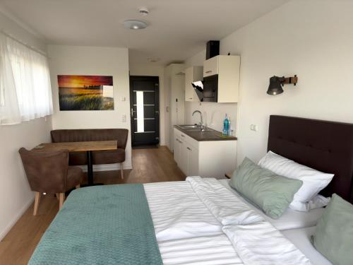 Fernweg Apartments في Nidderau: غرفة نوم بسرير وطاولة ومطبخ