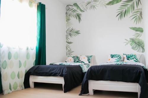2 camas en una habitación con cortinas verdes y blancas en Or'Delice Residence, en Antananarivo