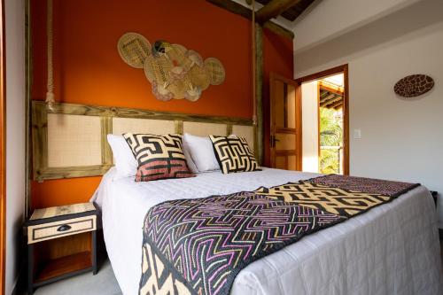 a bedroom with a large bed and an orange wall at Barlavento Villas in Ilhabela