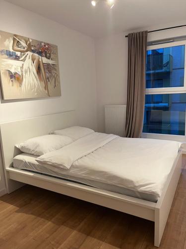 1 cama blanca en un dormitorio con ventana en Komfortowe Apartamenty z Garażem na Milionowej, en Łódź