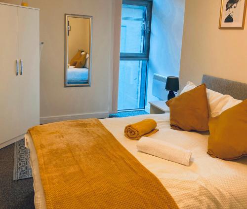 Un dormitorio con una cama con almohadas amarillas y una ventana en stylish two bed in the heart of the city en Birmingham