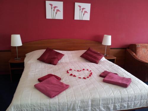 a bed with red pillows and a heart on it at Hotel Centrum Harrachov in Harrachov