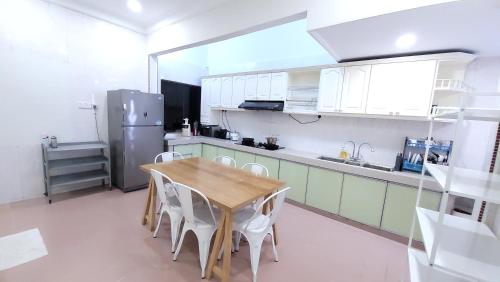 uma cozinha com uma mesa de madeira e armários brancos em The Penggawa Homestay - 3 comfortable bedrooms em Johor Bahru