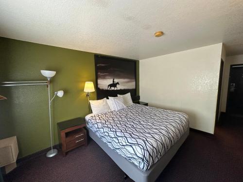 a hotel room with a bed and a painting on the wall at Simple Rewards Inn in Ruidoso