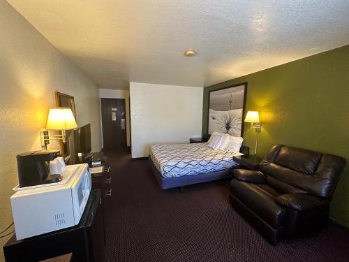 ein Hotelzimmer mit einem Bett, einem Sofa und einem TV in der Unterkunft Simple Rewards Inn in Ruidoso