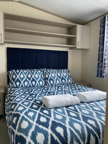 a blue and white bed with two pillows on it at Beautiful Cornish Getaway, Static Caravan - Newperran Holiday Resort in Cubert
