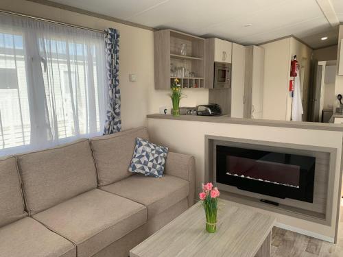 a living room with a couch and a fireplace at Beautiful Cornish Getaway, Static Caravan - Newperran Holiday Resort in Cubert