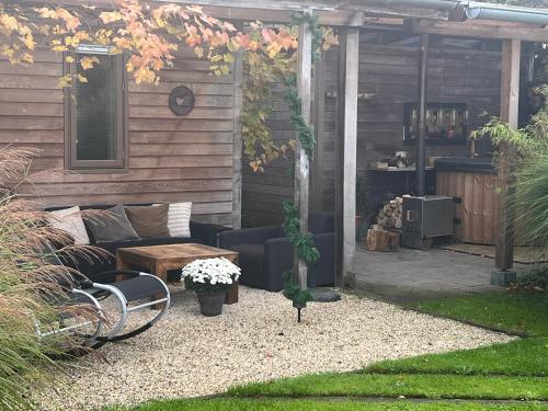 a patio with a couch and a bench and a table at De Aagt Tuyn in Schoorl