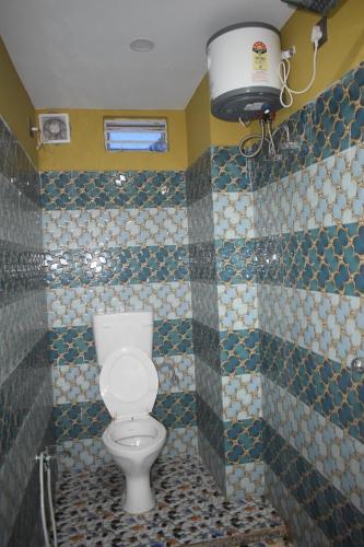 a bathroom with a toilet and a tiled wall at Airport Lodge in Siliguri
