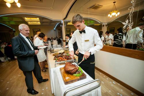 a man is cutting a cake at a buffet at Piastun SPA&Wellness Krynica-Zdrój in Krynica Zdrój