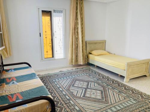 a bedroom with a bed and a rug and a window at Djerba Dar BAYA in Houmt Souk