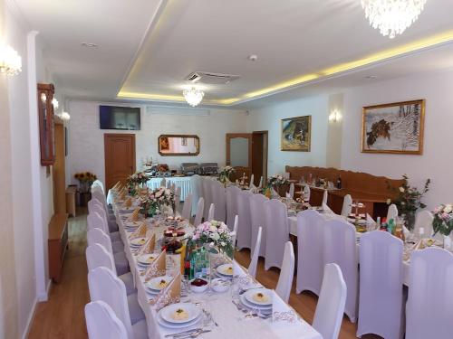 a banquet room with white tables and white chairs at Piastun SPA&Wellness Krynica-Zdrój in Krynica Zdrój