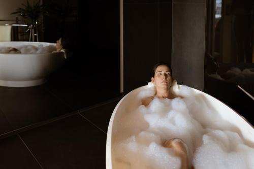 une femme assise dans une baignoire dans une salle de bains dans l'établissement Culinaria living, à Tirolo