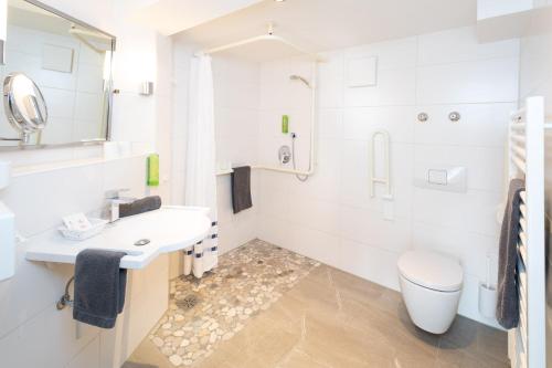 a white bathroom with a toilet and a sink at Familien- und Wellnesshotel "Viktoria" in Oberstdorf