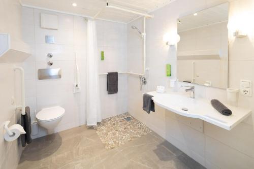 a white bathroom with a toilet and a sink at Familien- und Wellnesshotel "Viktoria" in Oberstdorf