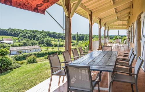 a wooden table and chairs on a porch with a view at Les Marronniers in Bourgougnague
