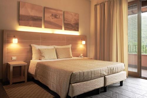 Meridiana Country Hotel في كالينسانو: غرفة نوم بسرير كبير ونافذة كبيرة
