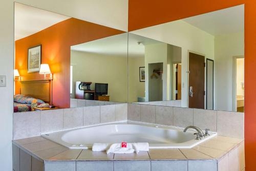 a bath tub in a room with a large mirror at Econo Lodge Inn & Suites Pritchard Road North Little Rock in North Little Rock