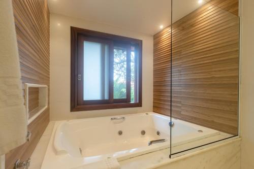 a bath tub in a bathroom with a window at Corais e Conchas in Búzios