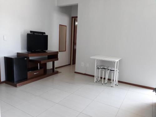 sala de estar con TV, mesa y taburete en Centrinho Canasvieiras 202 2 andar, en Florianópolis