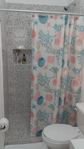 a bathroom with a shower curtain with a toilet at Casa Tauch in Cancún