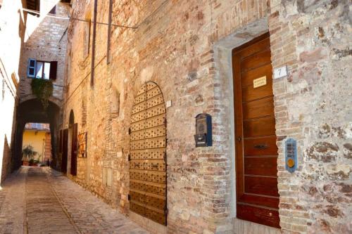 un callejón con puerta de madera en un edificio de ladrillo en Residenza San Jacopo, en Spello