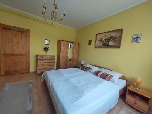 - une chambre avec un grand lit blanc et des murs jaunes dans l'établissement schönes Ferienhaus mit grossem Pool 4 km zum Balaton, à Balatonszentgyörgy