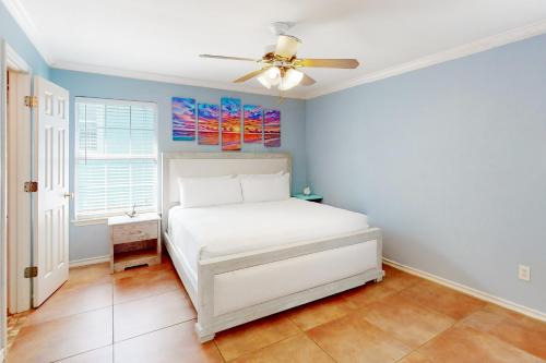 een slaapkamer met een wit bed en een plafondventilator bij Flamingo Lagoon in Corpus Christi