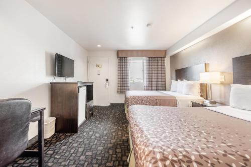 Cette chambre comprend deux lits et une télévision. dans l'établissement City Creek Inn & Suites, à Salt Lake City