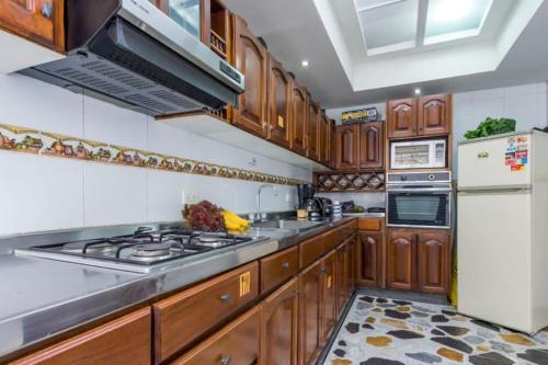 a kitchen with wooden cabinets and a stove top oven at Casa Quimbaya in Armenia