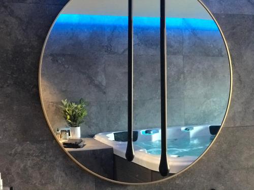 a round mirror in a bathroom with a tub at L’ODYSSÉE SPA in Seclin