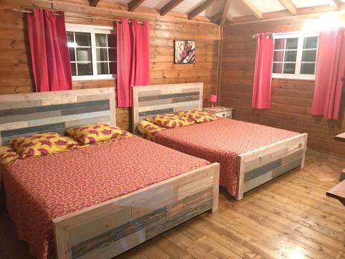 two beds in a room with wooden walls and windows at Villa panoramique à Pointe-Noire avec vue sur mer et piscine in Pointe-Noire