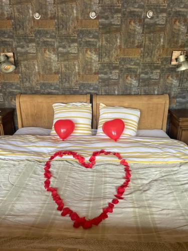 two hearts are on a bed with two pillows at Gite Au champ du bouillon proche de Pairi Daiza wellness en option in Chièvres