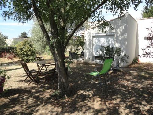 a picnic table and a green chair under a tree at Gite L ABRI COSTIER in Villeveyrac