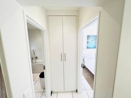 Quebec Apartments - Fully Furnished & Equipped 1 Bedroom Apartment في Sandton: غرفة بيضاء ذات بابين ومرآة
