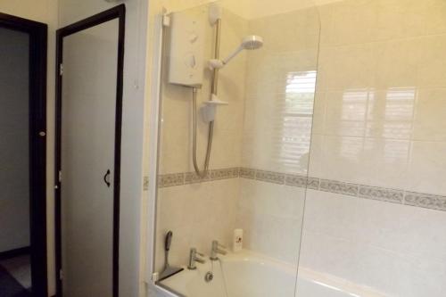 a bathroom with a tub and a shower with a mirror at Dairy Cottage, Dulverton in Dulverton