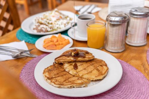 a table topped with plates of pancakes and orange juice at Hotel Meson de Carolina in Querétaro